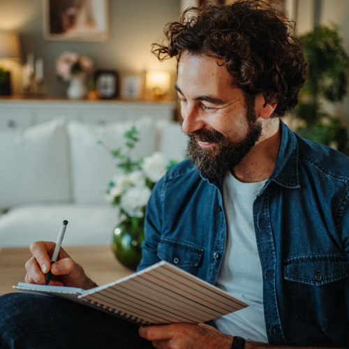 A happy man writing or drawing in a book.
