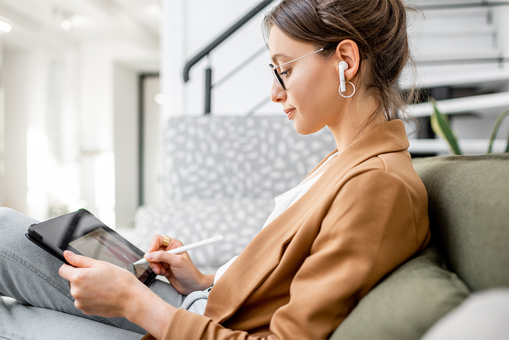 Young woman drawing on her tablet while listening to music or audiobooks